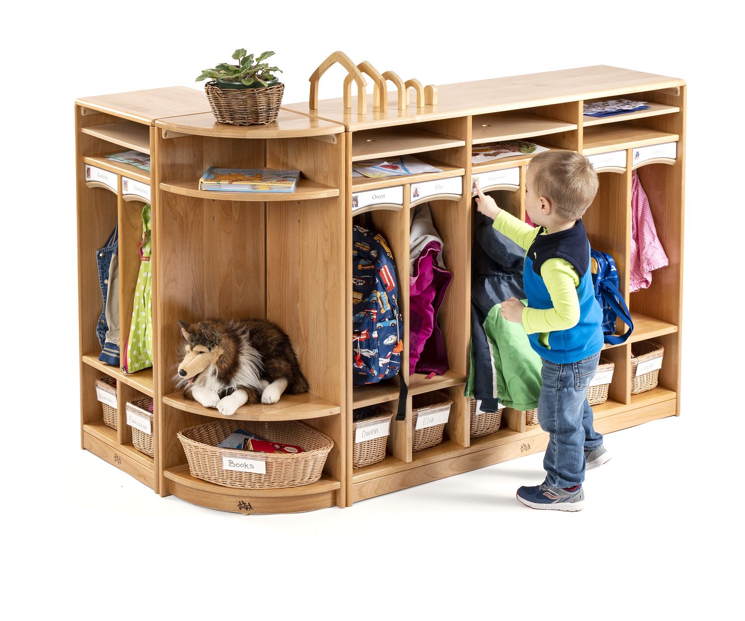 A boy is standing in front of two cubbies which are connected with a Cubby Corner Shelf