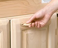 A hand holds a plastic key in front of a cabinet door with locking feature