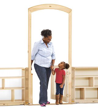 A teacher and a child walk through an arch