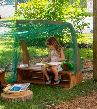 Girl reading a book seated under the Outlast Arbor