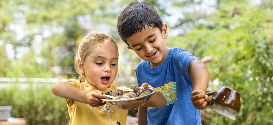 two kids playing in a mud kitchen