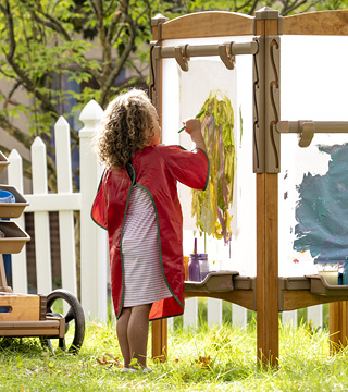 preschool girl painting on outdoor easel