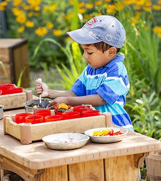 a boy playing in a mud kitchen