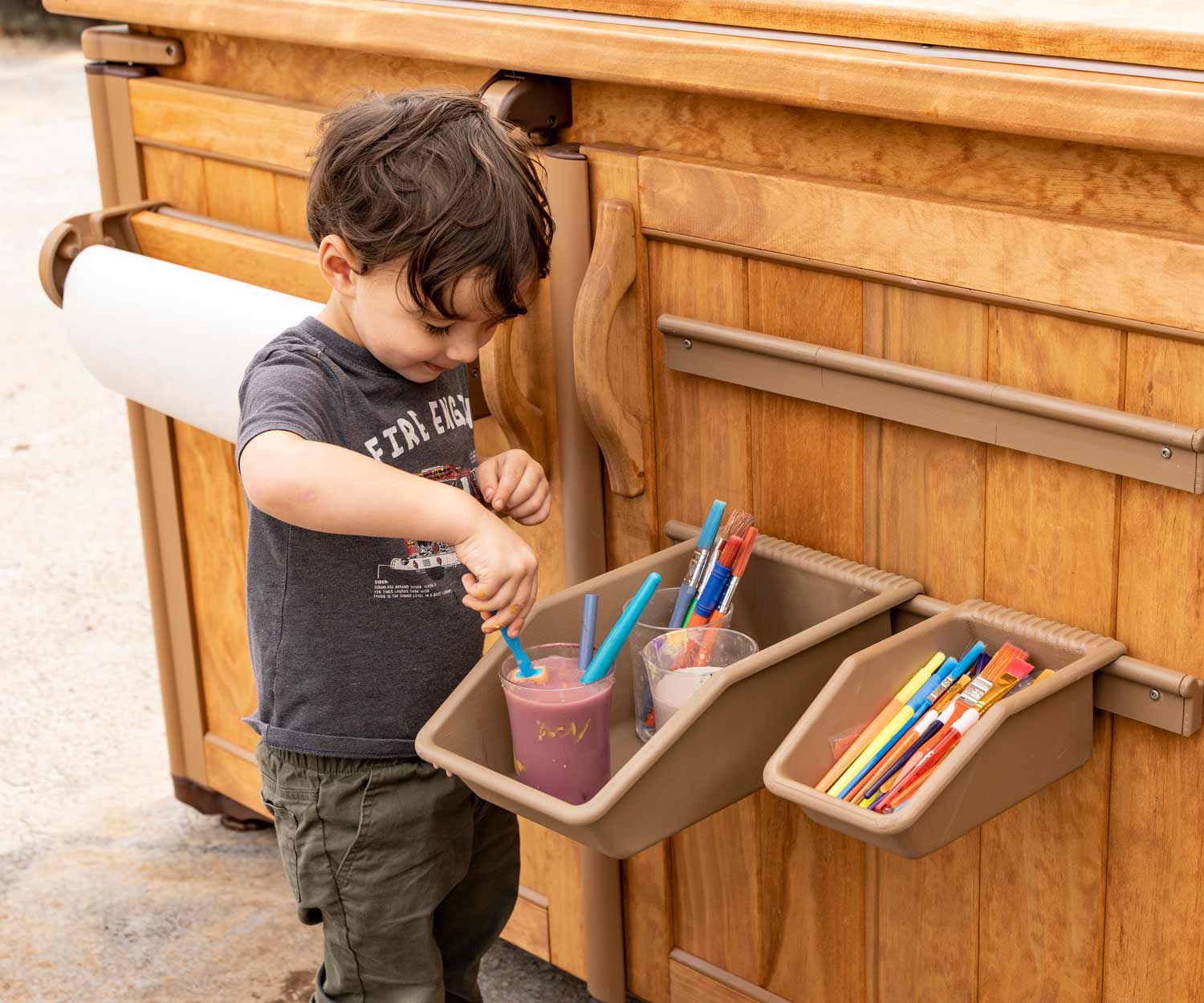child playing with paint brushes on outlast shed