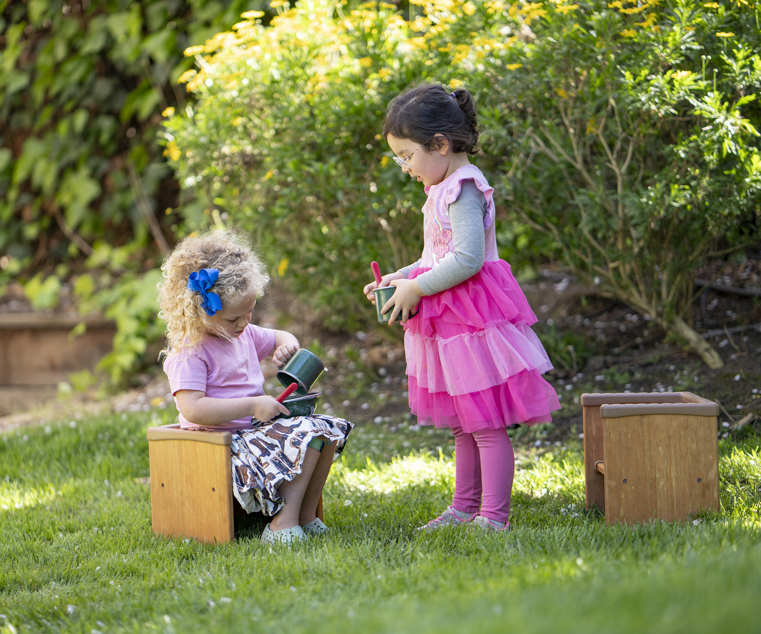 two little kids with wooden outdoor chairs