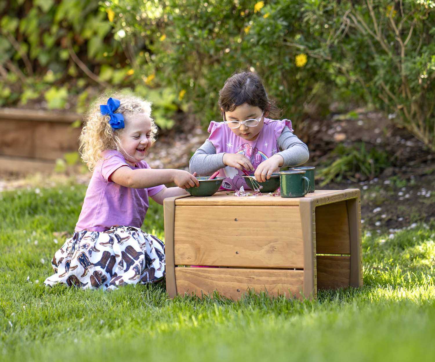 two little kids with a tiny wooden outdoor table