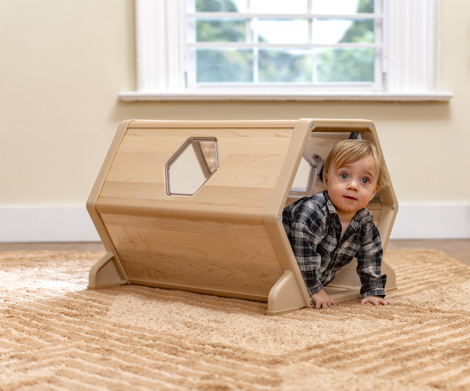 A toddler playing in a wooden tunnel