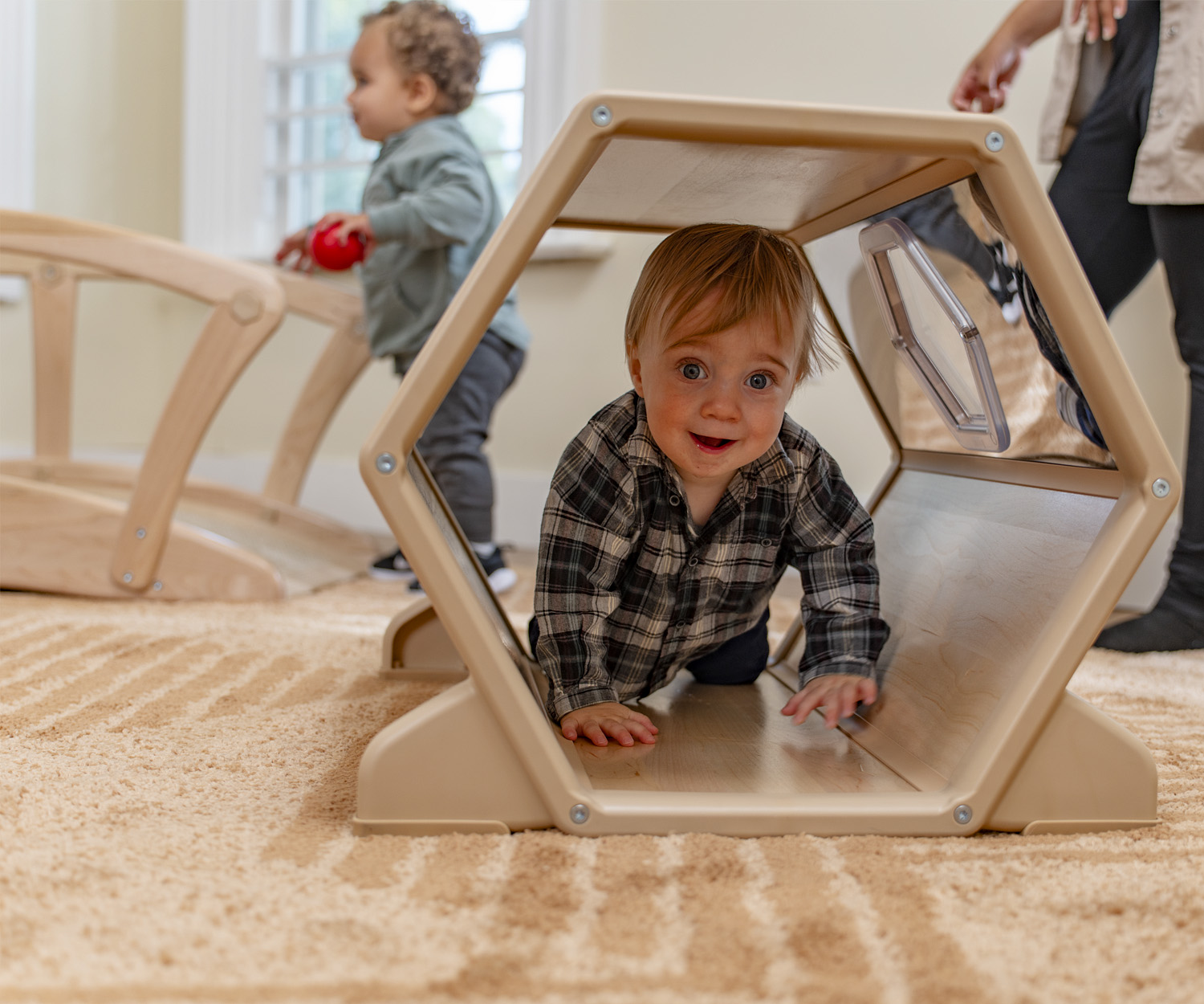 A toddler playing in a wooden tunnel