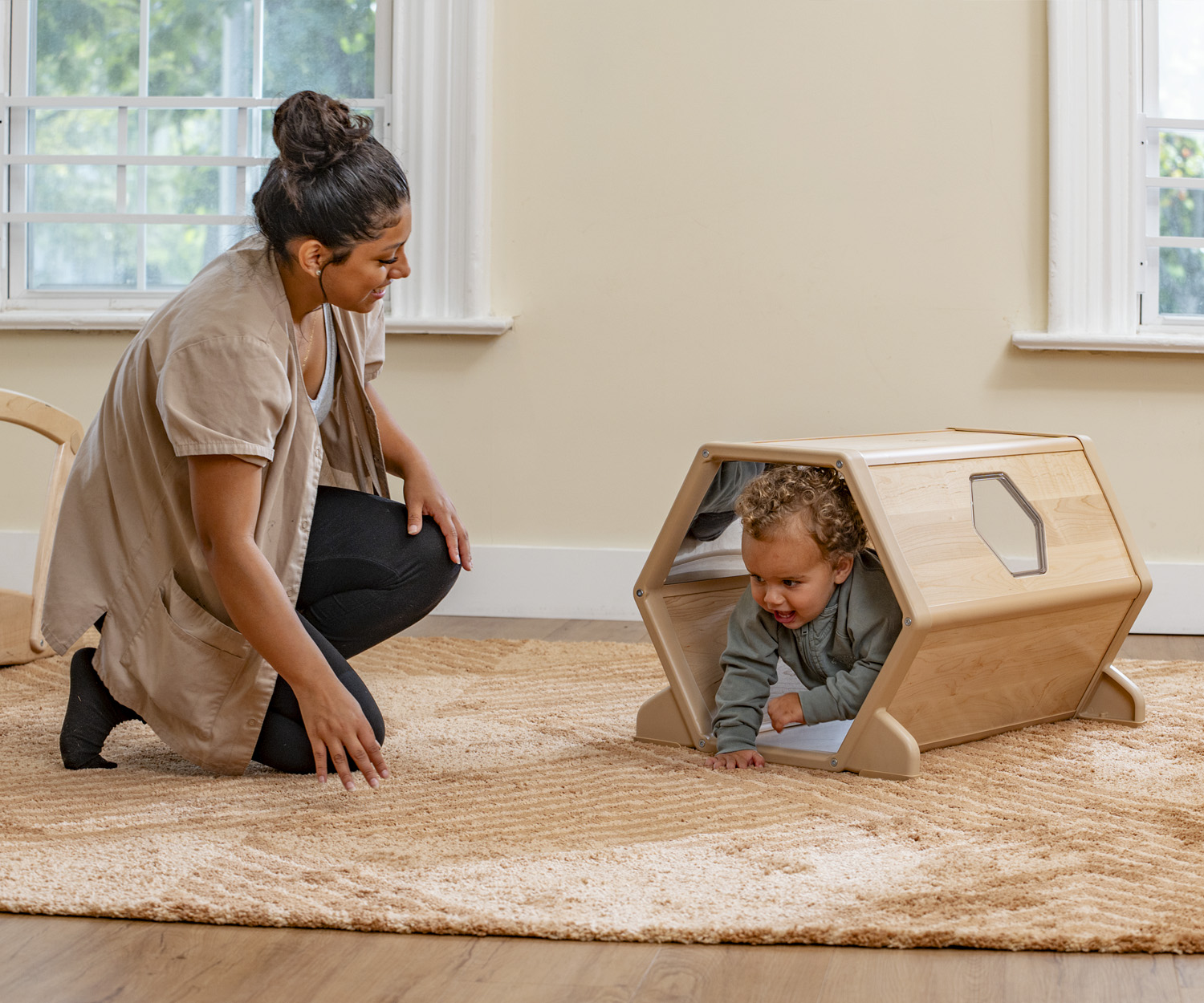 A toddler playing in a wooden tunnel