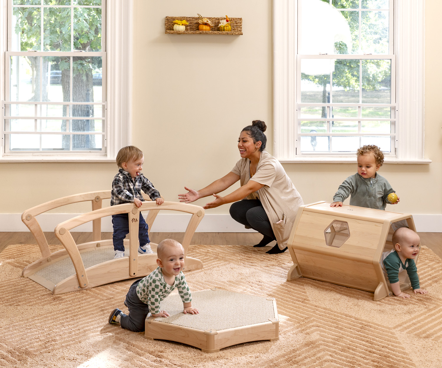 toddlers playing on a bridge and tunnel in the toddler classroom