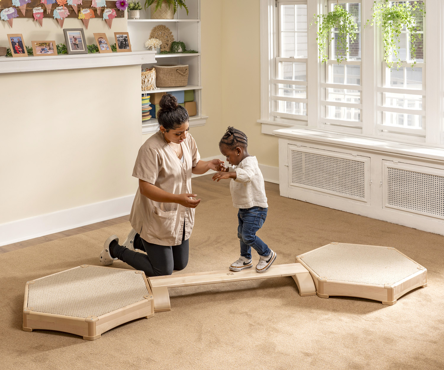 a teacher helping a toddler to walk on a balancing beam