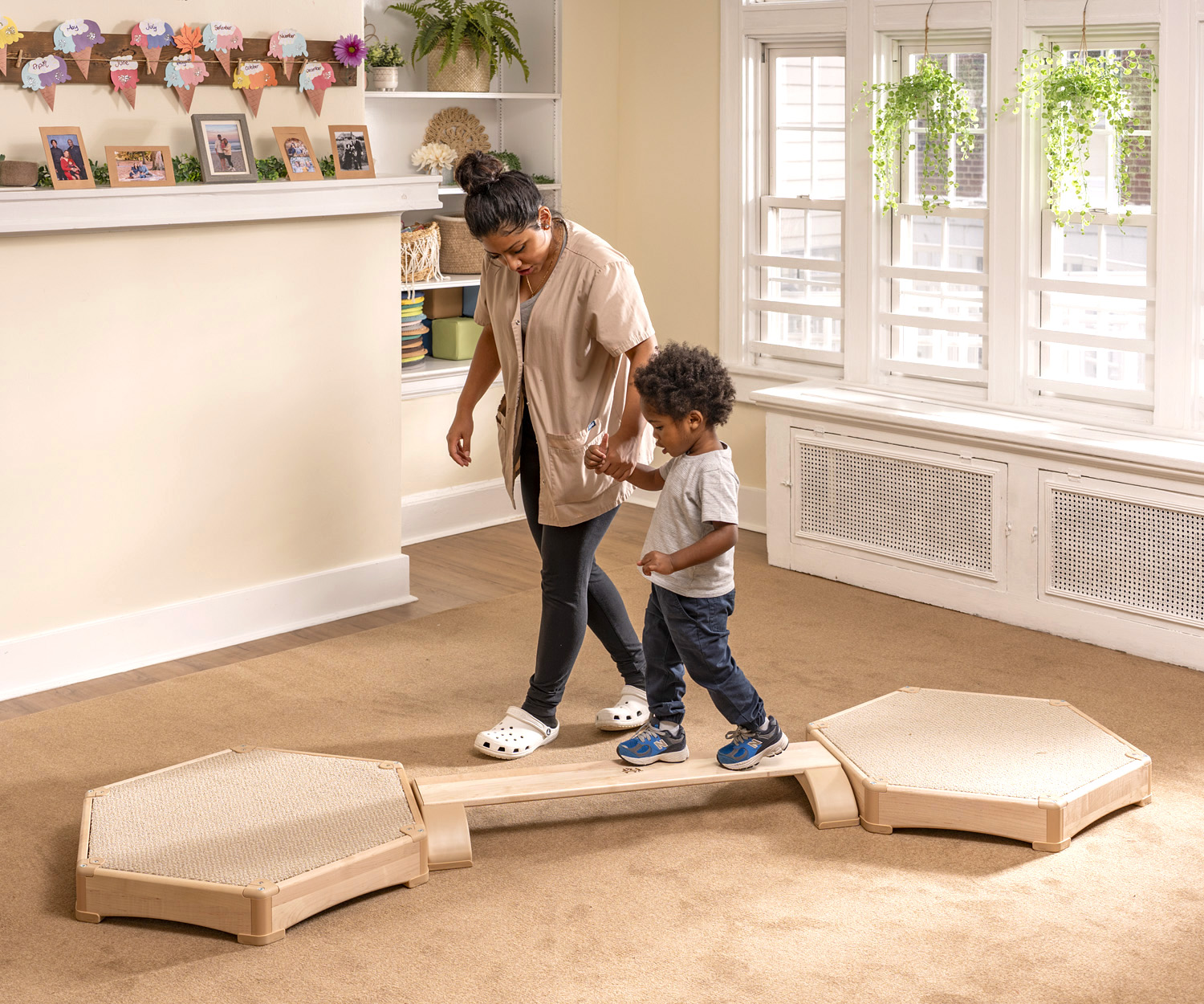 a teacher helping a toddler to walk on a balancing beam