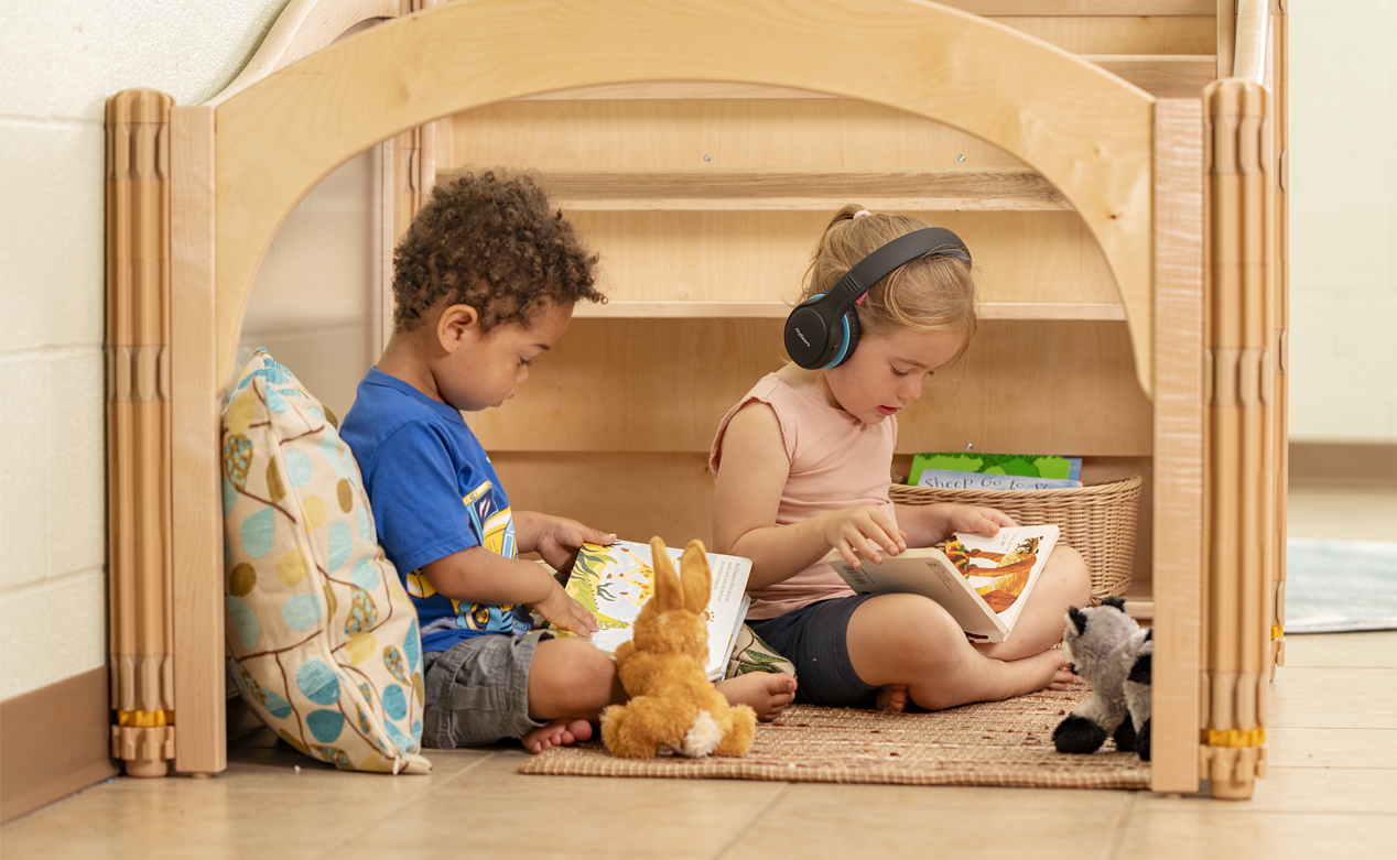Two children reading books in a Community Playthings Listening Cube