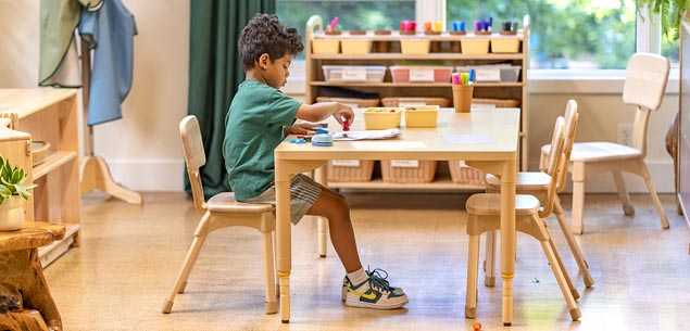 Child seated on classroom chair doing artwork