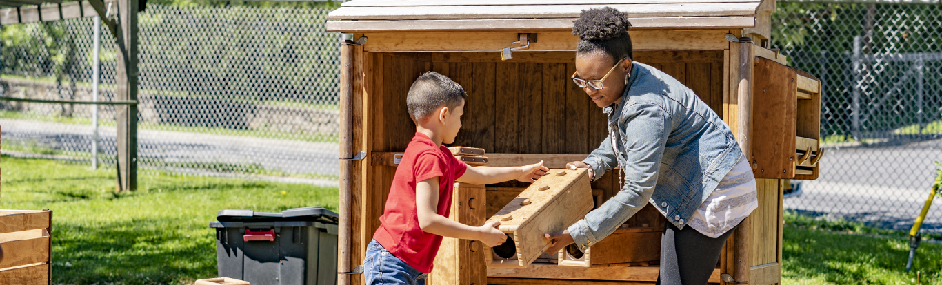 A teacher and child packing blocks away