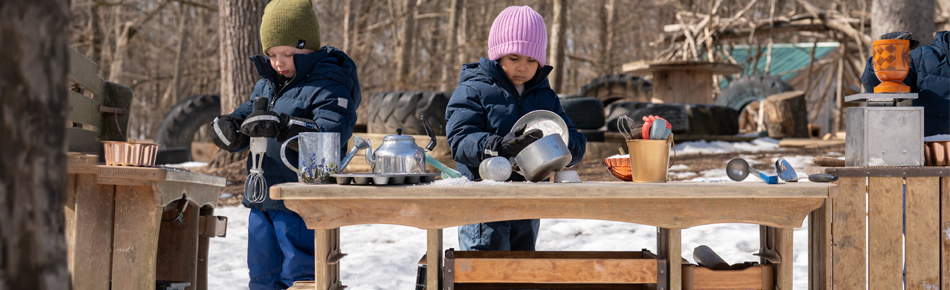 Children playing outdoors in the snow with Outlast Mud Kitchen