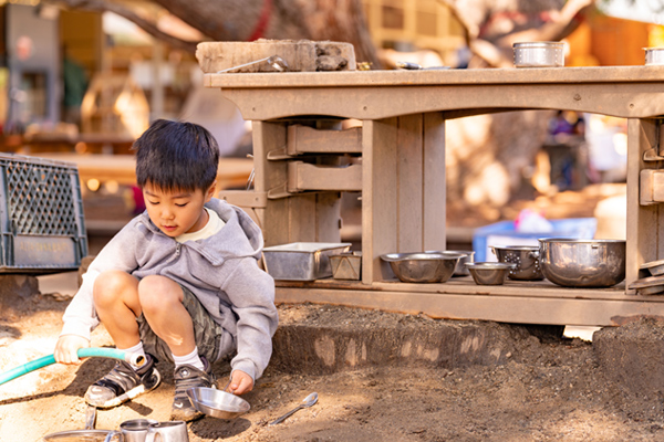 Boy playing in front of beautifully aged mud kitchen